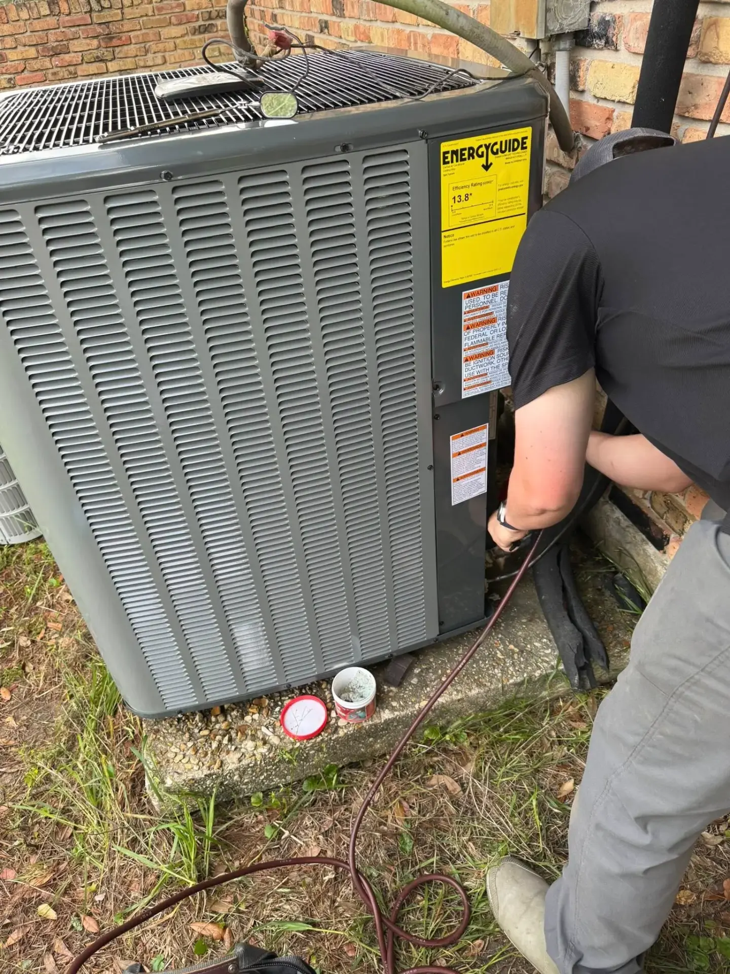 Technician servicing outdoor HVAC unit during maintenance visit